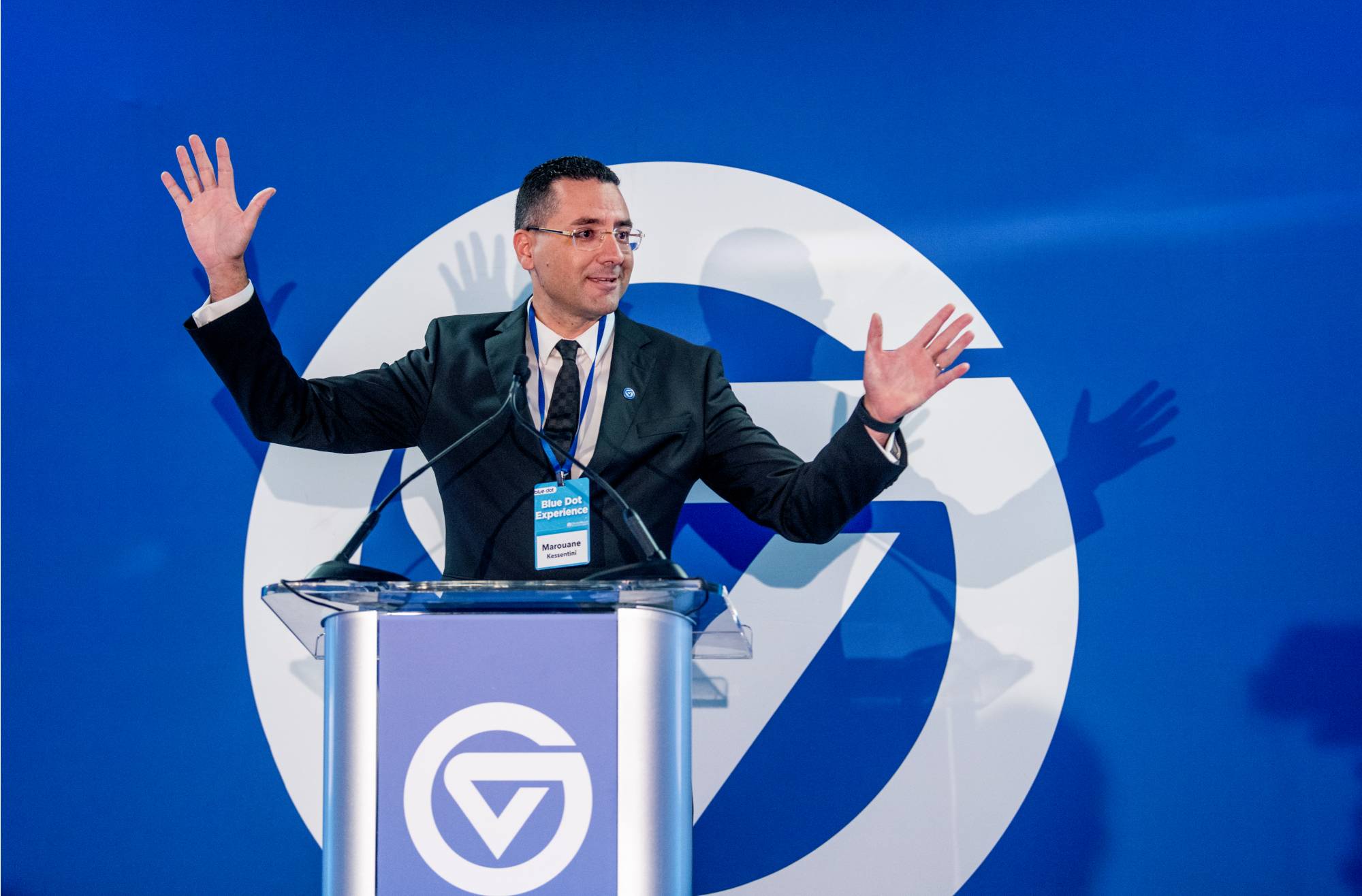 Photo of Dean Kessentini infront of GVSU podium at the Blue Dot